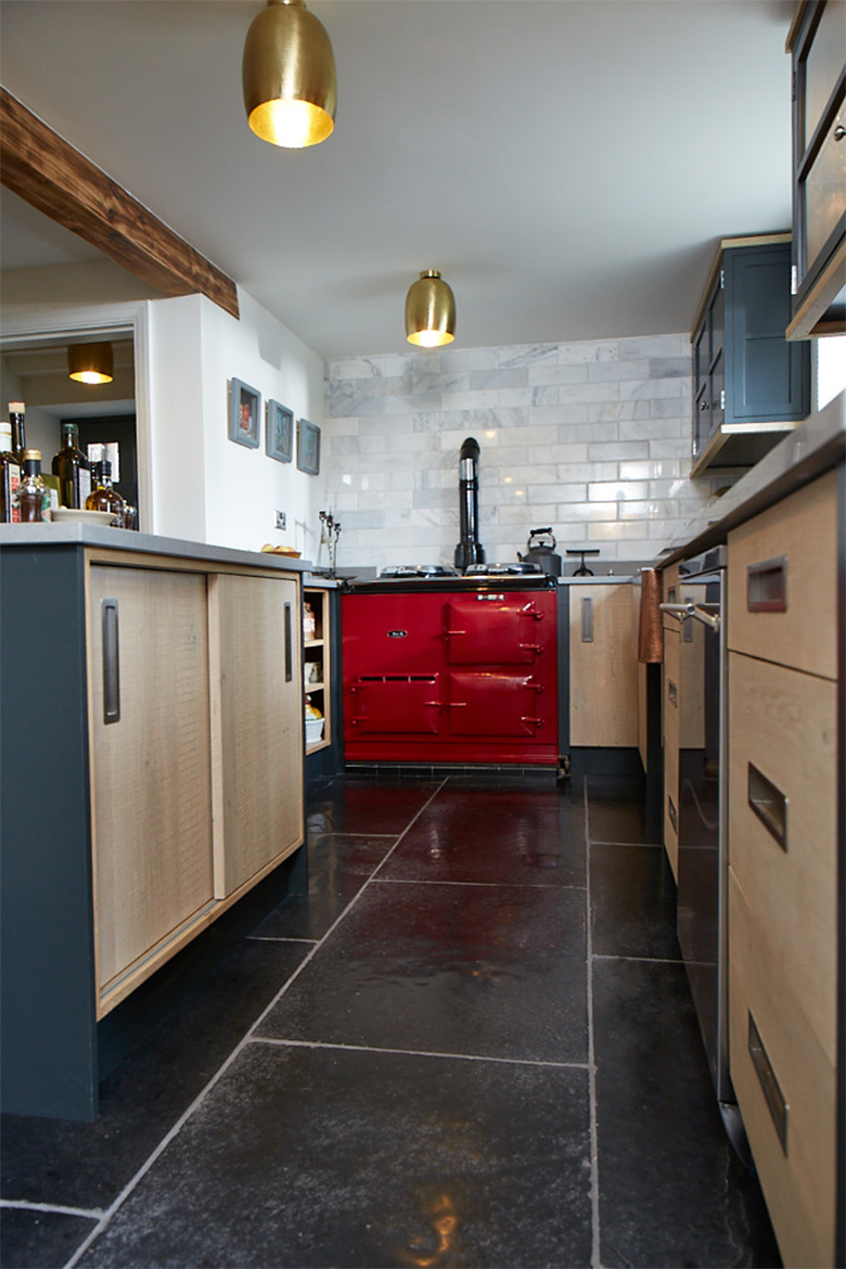 Red Aga and bespoke oak kitchen units with painted little green posts and caesarstone worktops