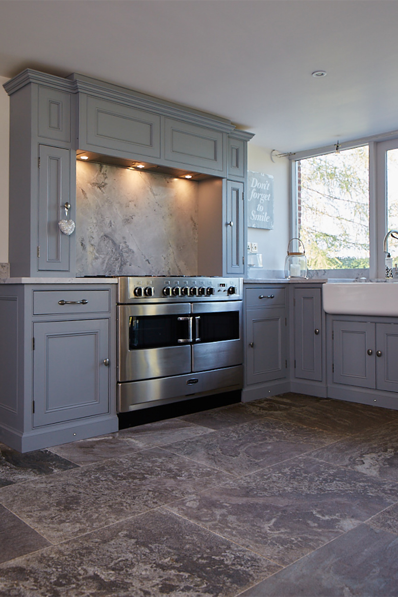 Stainless steel oven sits within bespoke painted kitchen cabinets on mantle housing extractor