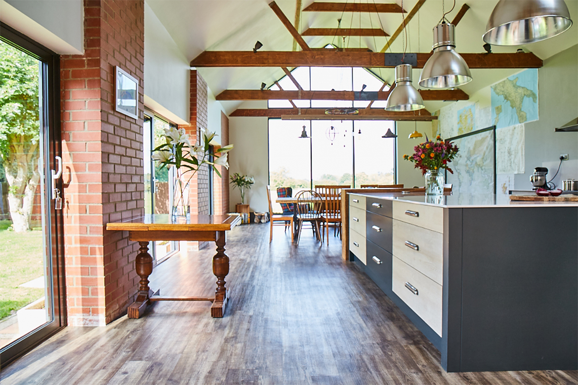 High vaulted room with bespoke kitchen island and antique table