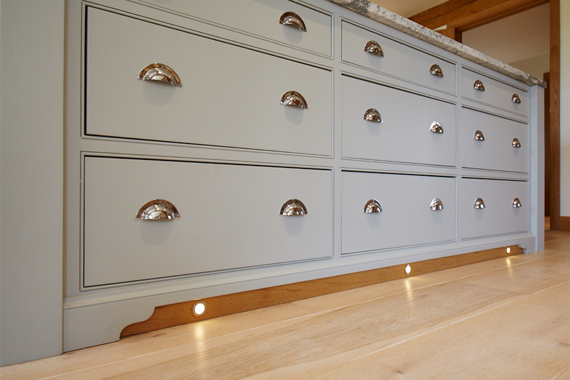 Close up of solid oak plinth with lights and chrome cup handles on drawer fronts