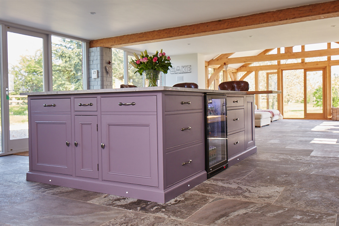Bespoke purple kitchen island with freestanding wine cooler and plinth lights