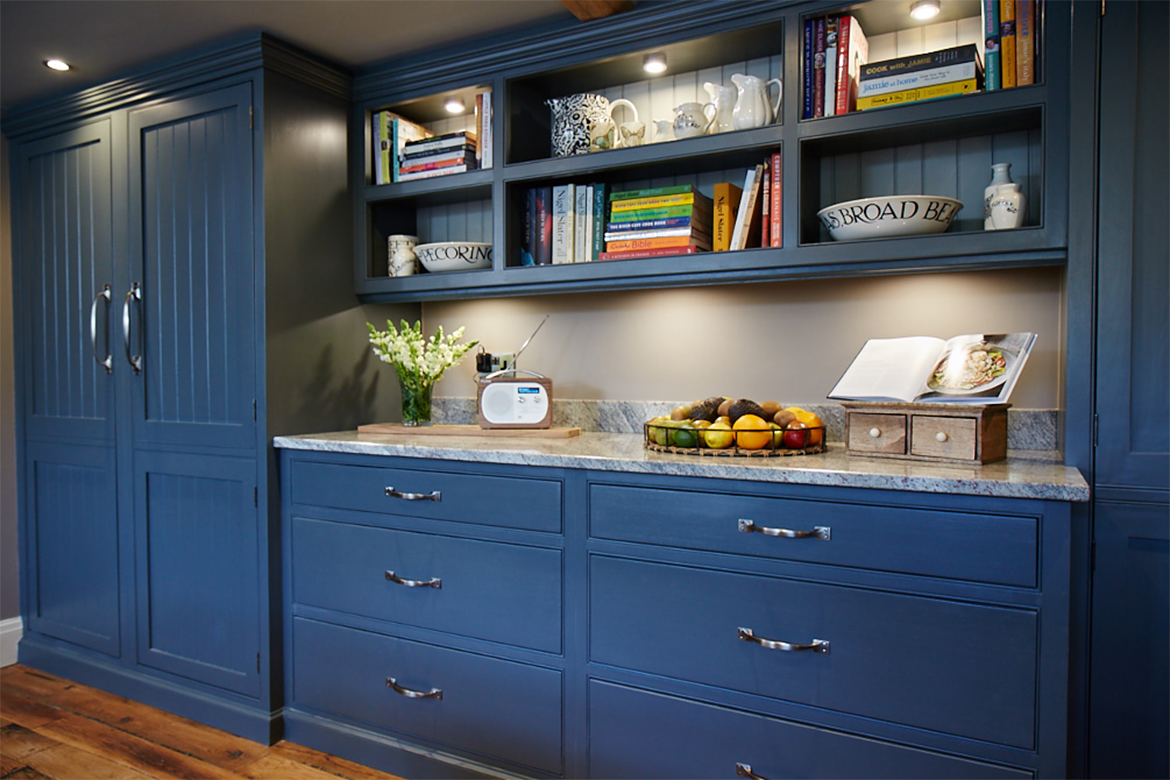 Bespoke painted open wall units filled with books and tall cabinets either side