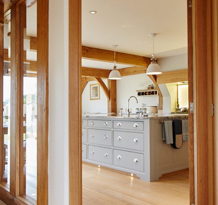View of the painted kitchen island with granite worktop through solid oak architecture frame