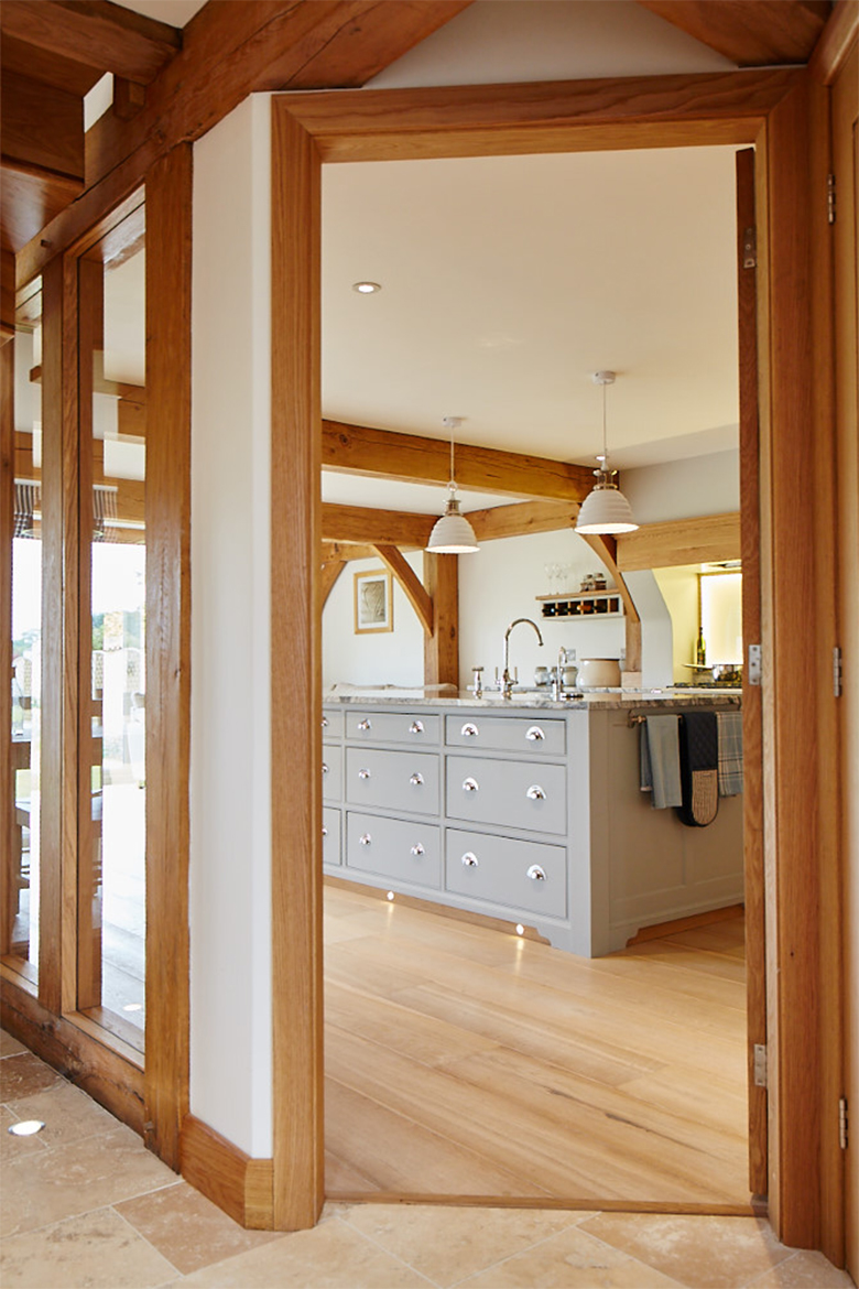 View of the painted kitchen island with granite worktop through solid oak architecture frame