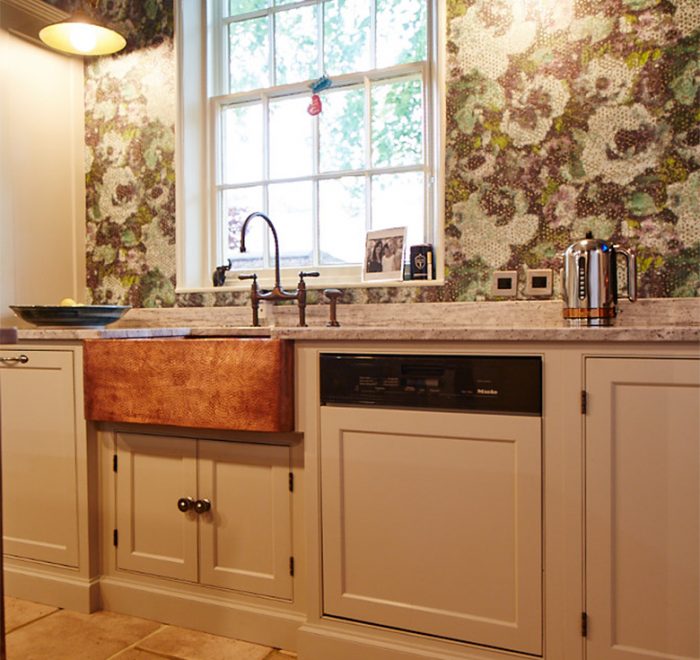 Bespoke painted kitchen run in Little Greene with integrated Miele dishwasher and beaten copper belfast sink with colourful green wallpaper