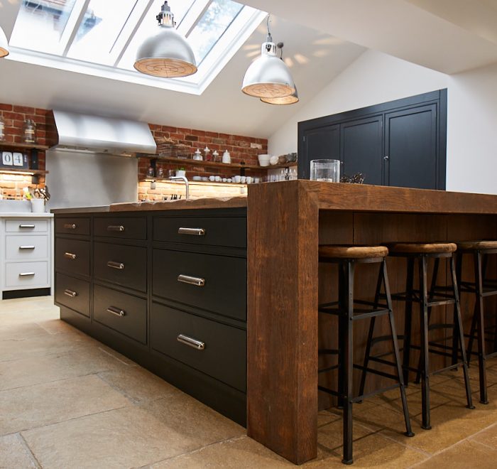 Bespoke kitchen island with chunky reclaimed oak breakfast bar wrap around and a stainless steel worktop