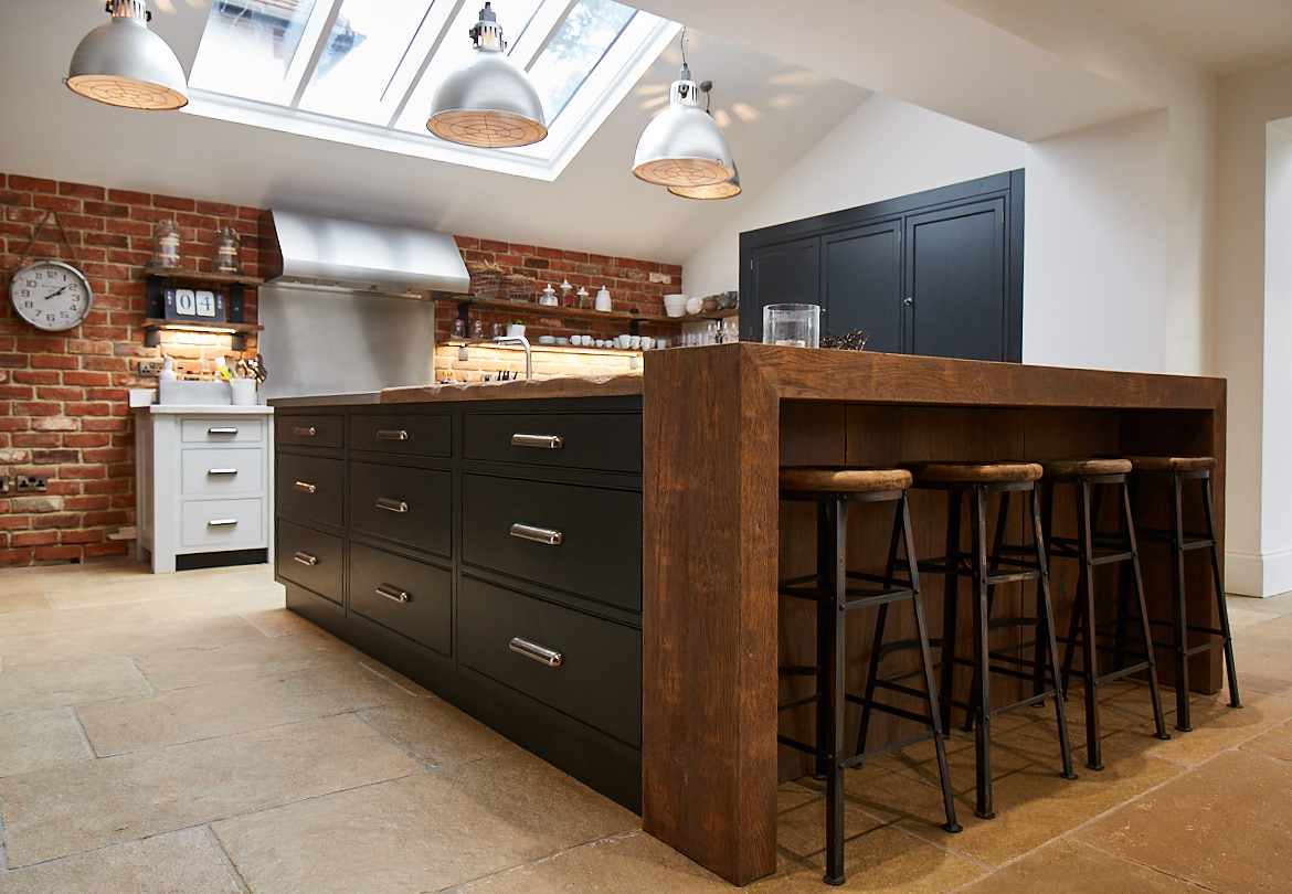 Bespoke kitchen island with chunky reclaimed oak breakfast bar wrap around and a stainless steel worktop