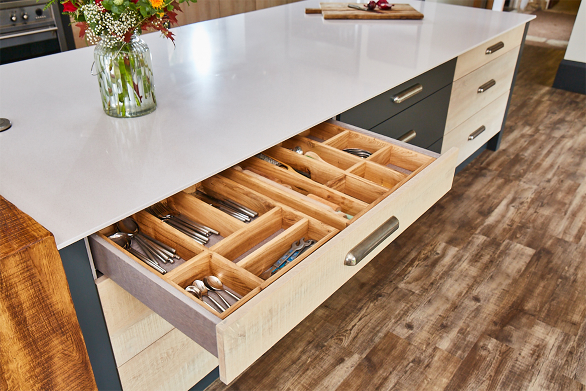 Bespoke kitchen drawer open with solid oak wood cutlery divider and dekton worktop