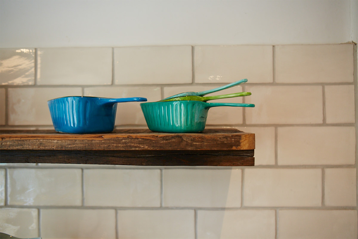 Colourful bowls on reclaimed oak shelves against white metro tiles