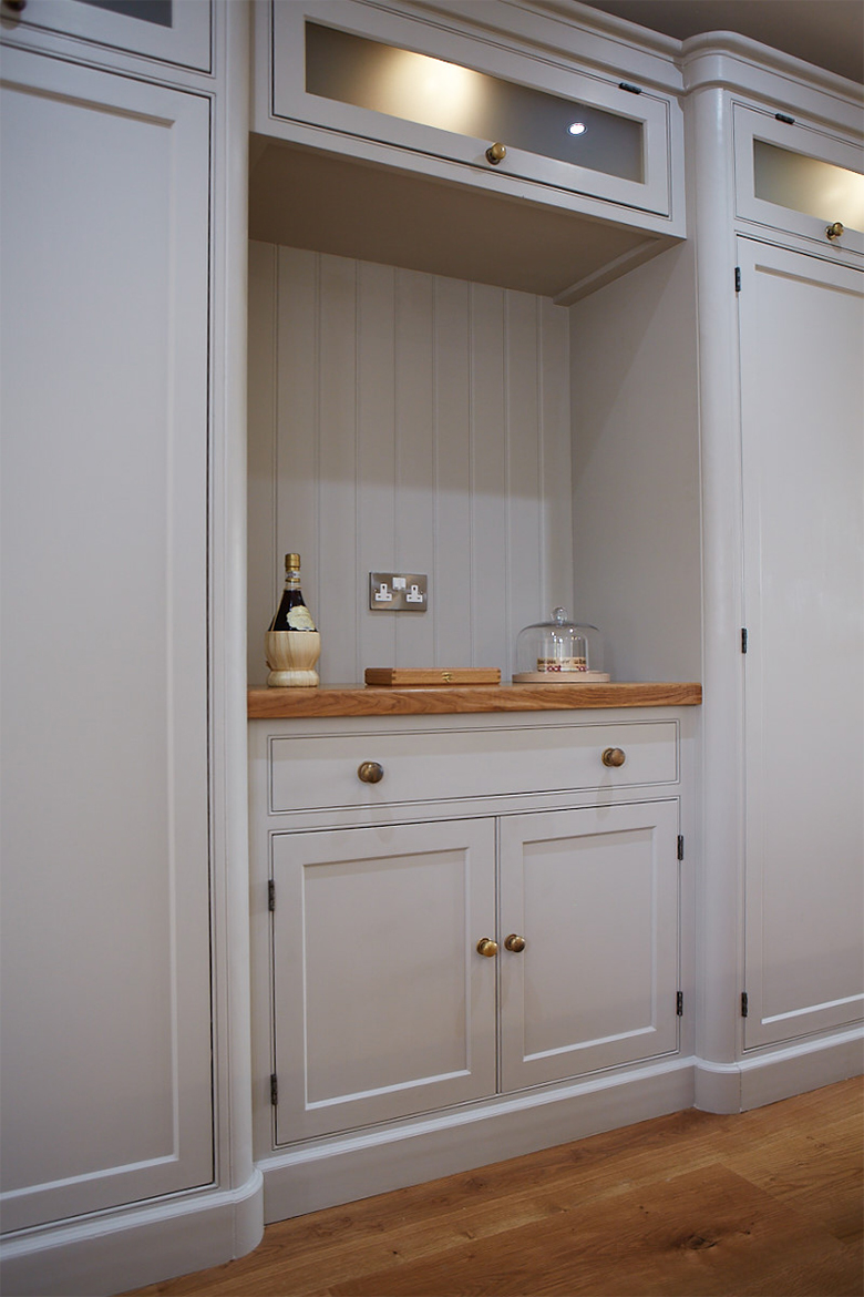 Bespoke kitchen cabinets painted in a light little greene colour with solid oak worktops and glazed wall cabinets
