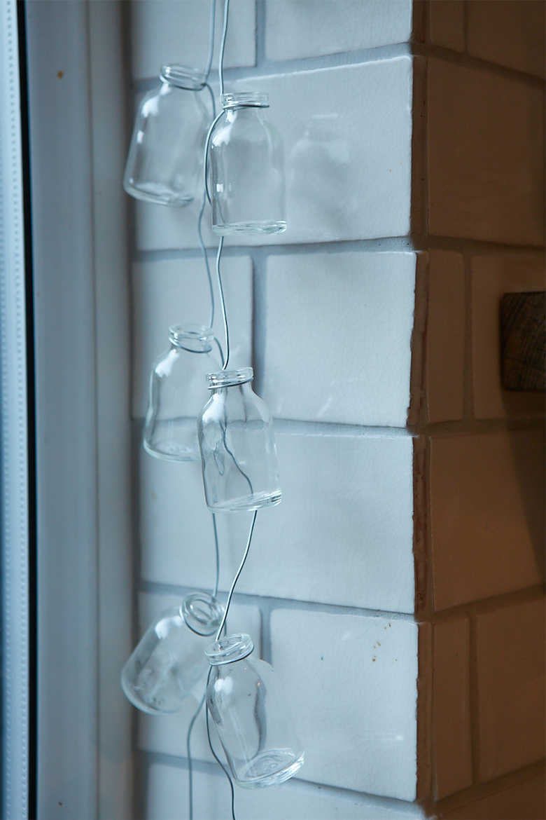 Milk bottles hanging from metal wire against white tiles