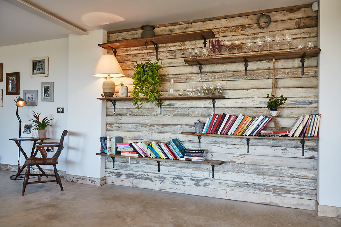 Flaky white reclaimed wall cladding with rustic bookshelves and cast brackets displaying cook books