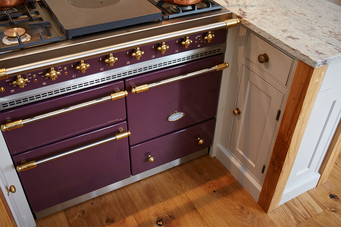 Classic plum macon lacanche with brass trim set in between painted bespoke cabinets with oak posts