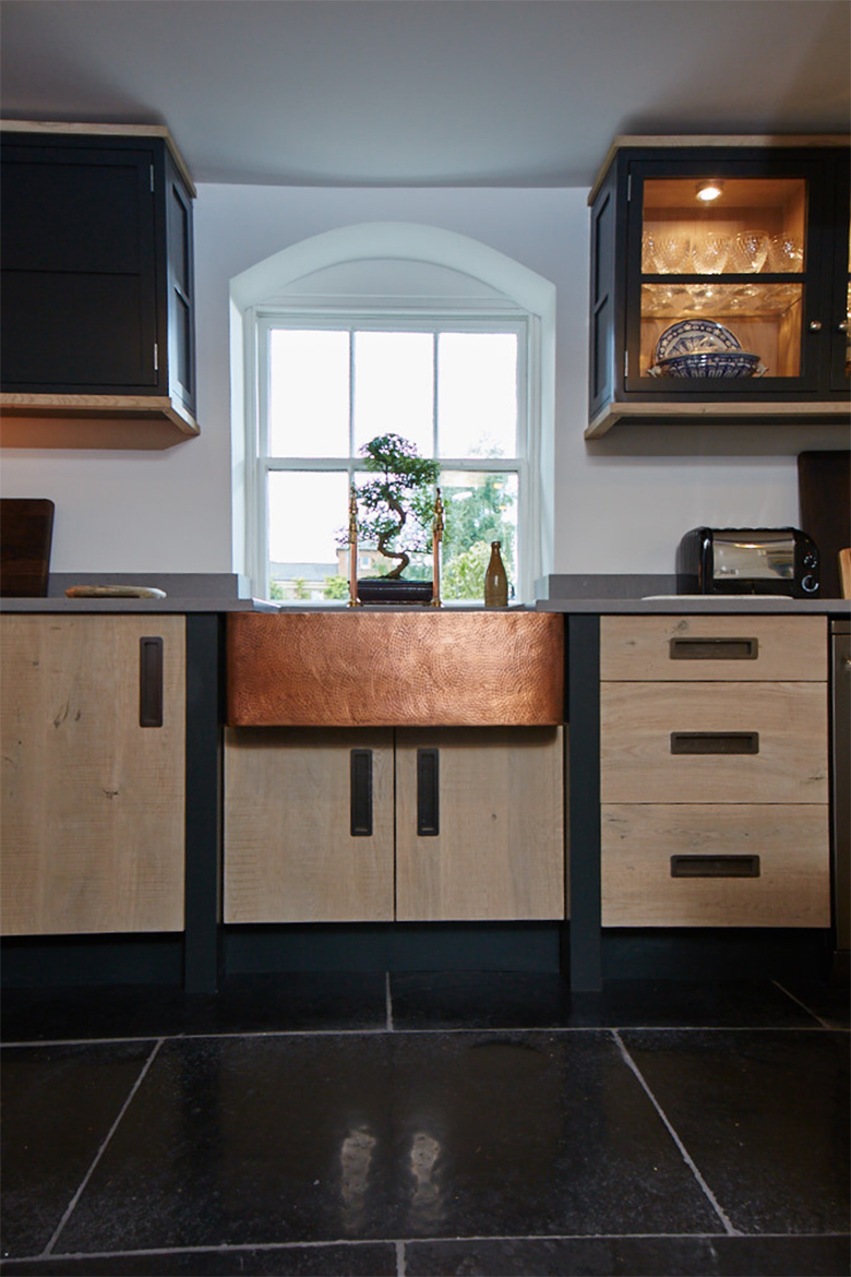 Bespoke engineered oak kitchen units with beaten copper belfast sink and dark painted posts