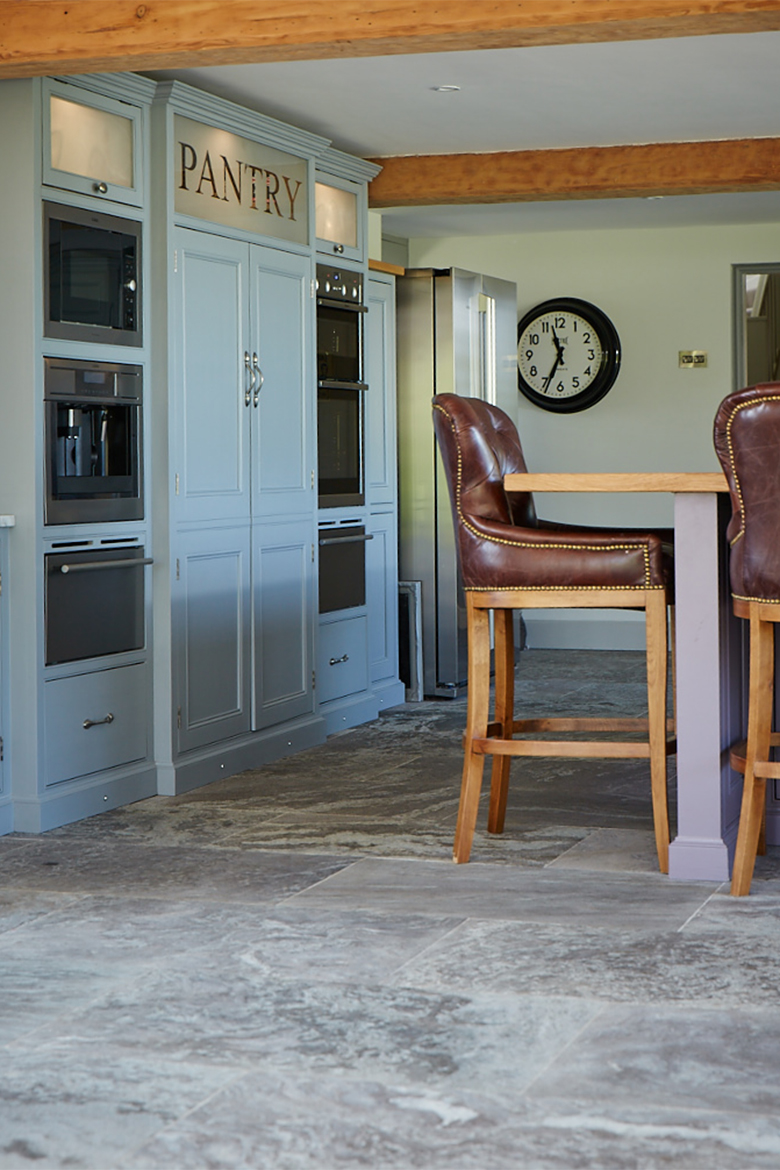 Leather bar stool sits in front of bespoke glazed painted pantry unit