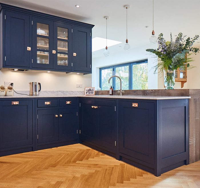Blue kitchen cabinets in l configuration on oak parquet flooring