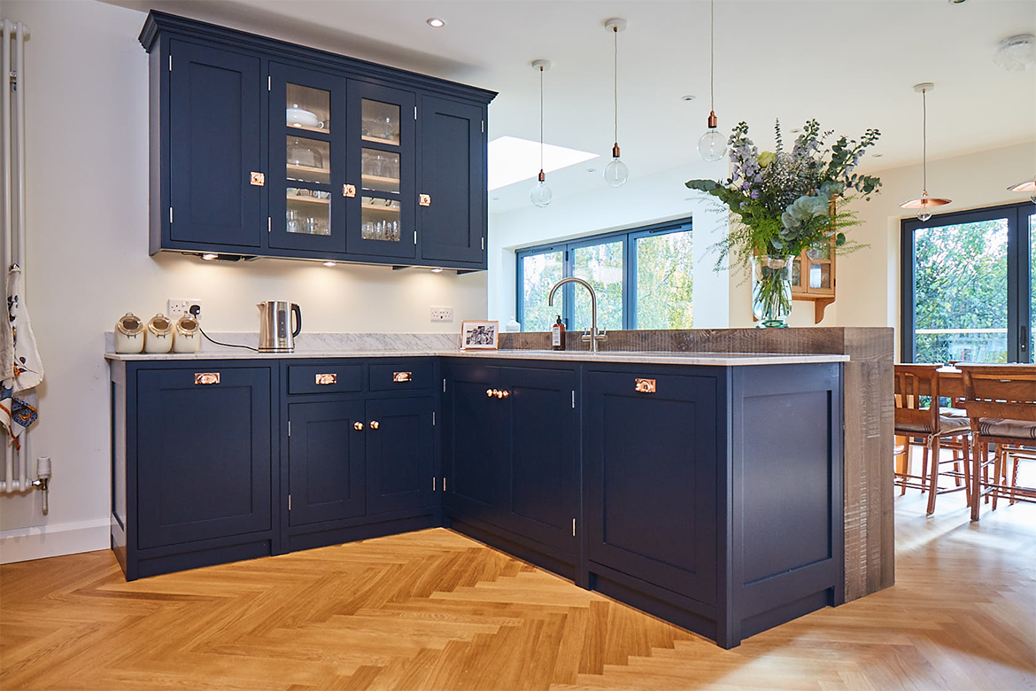 Blue kitchen cabinets in l configuration on oak parquet flooring