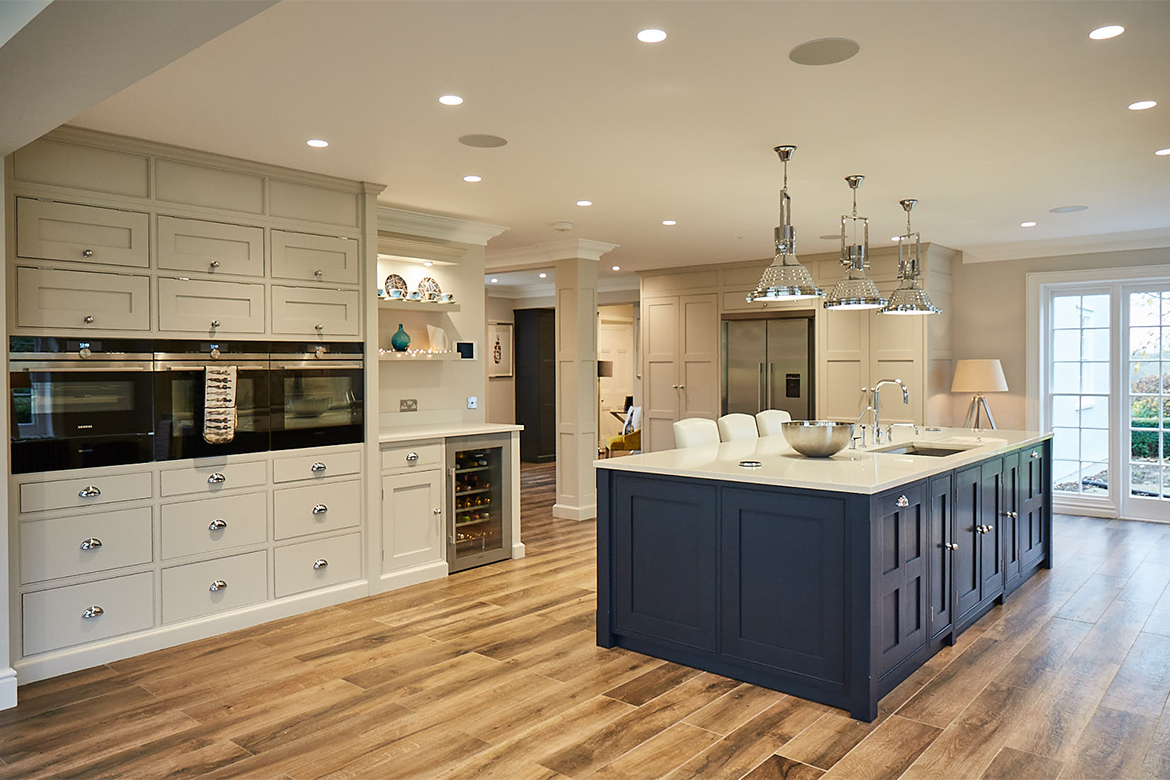 Bespoke kitchen island painted blue and tall oven units in light grey