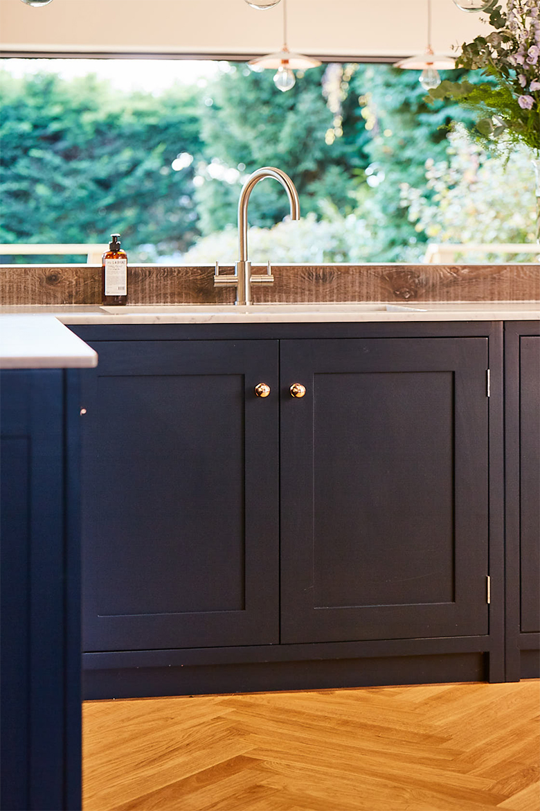 Dark blue double door shaker sink unit with stainless steel tap and cream quartz worktops