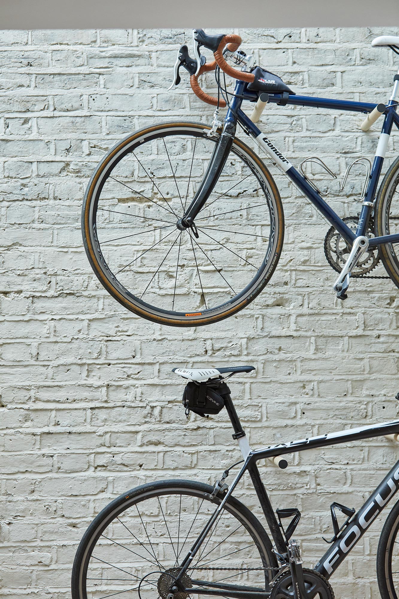 Bikes stored on painted white brick wall