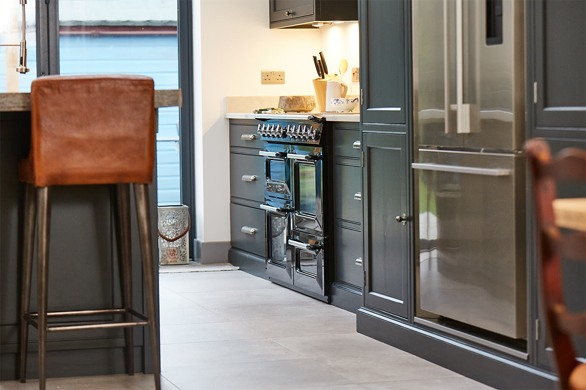 Black range cooker sits alongside fisher paykel stainless steel American fridge freezer and painted black units