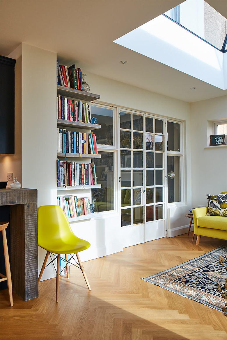 Living area with bookshelves next to large glass doors and oak parquet wood floor