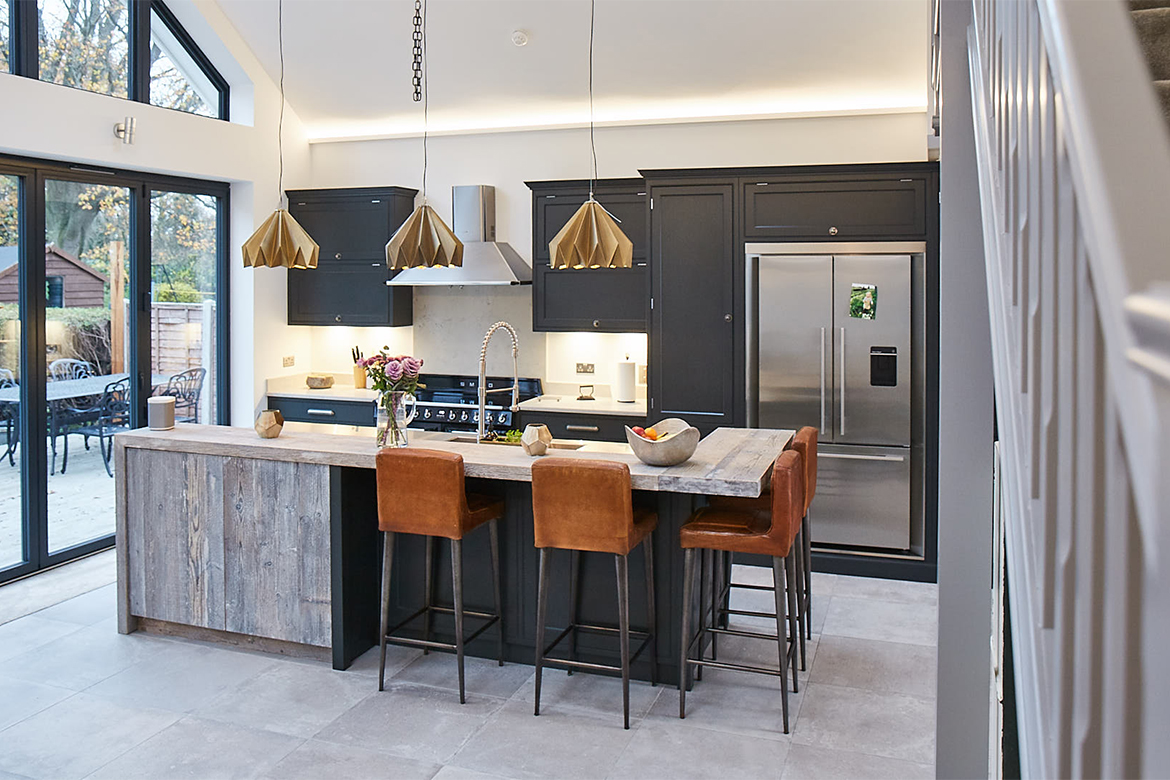 Stairs lead to industrial kitchen including reclaimed rustic breakfast bar and leather bar stools