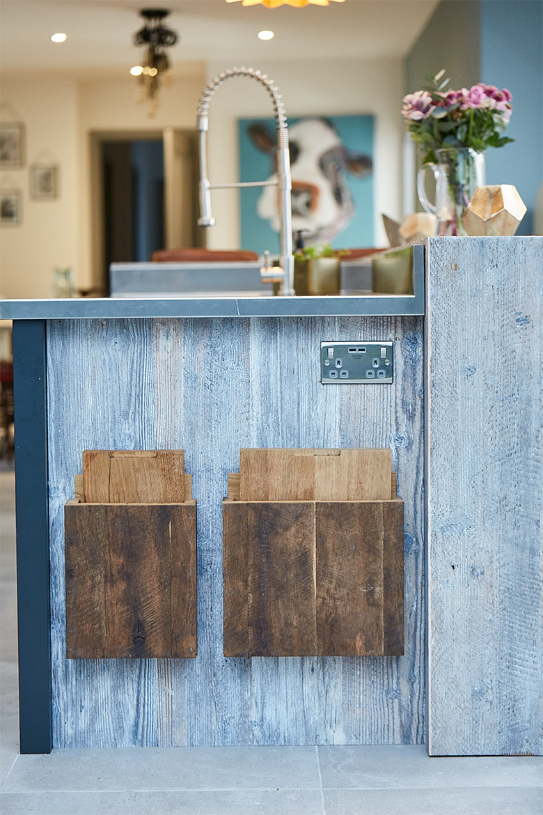 End panel of kitchen unit holds two oak chopping boards and has stainless steel plug socket mounted in to the side