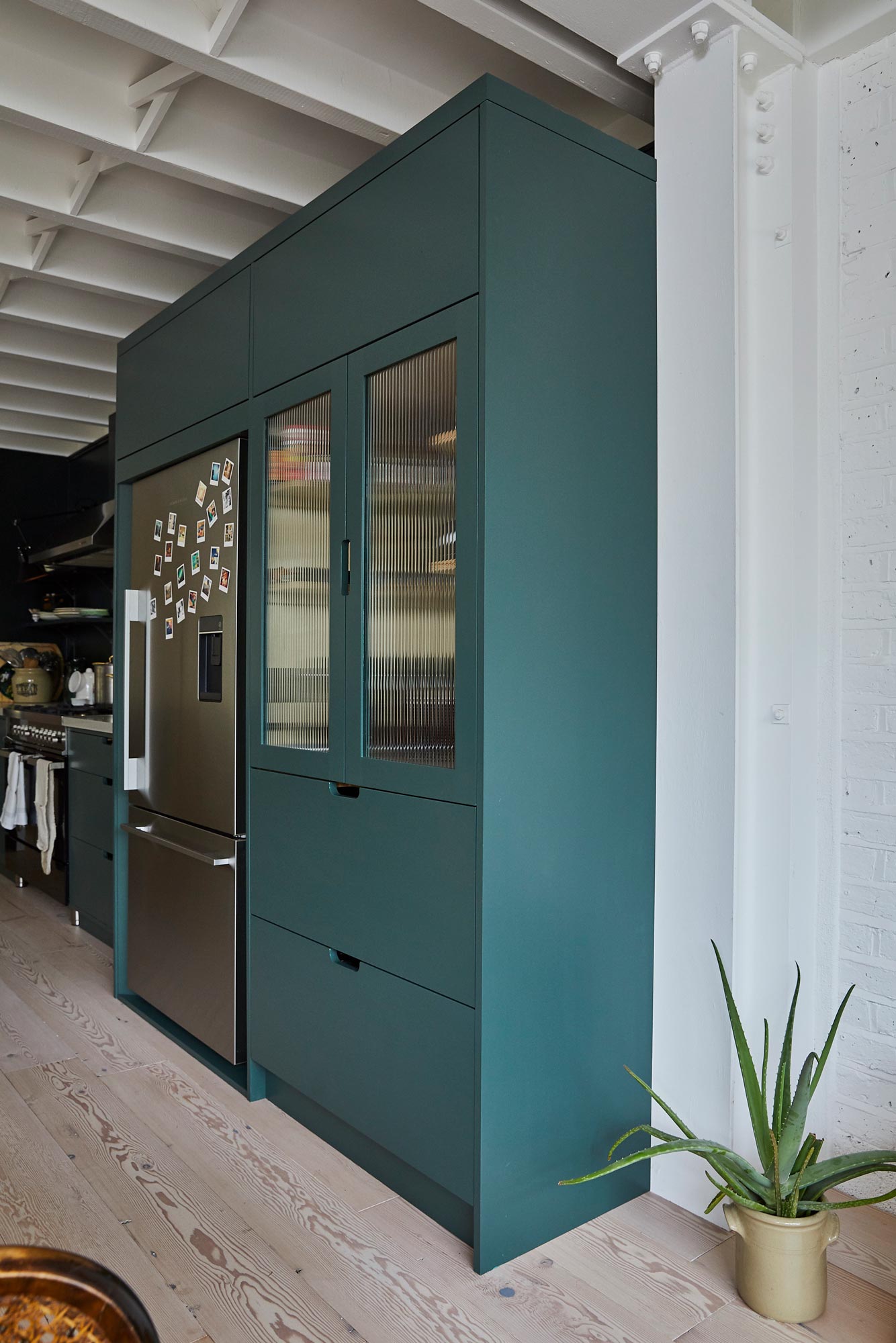 Green painted pantry unit next to stainless steel fridge freezer
