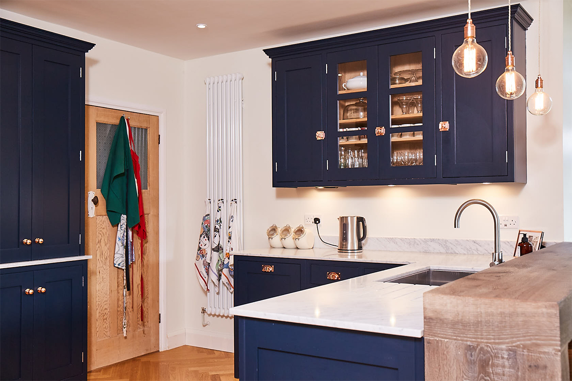 Three glass pendant lights above breakfast bar and white quartz worktop below