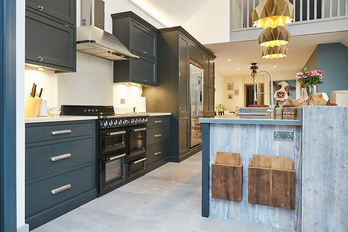 Black range cooker sits in between bespoke painted cabinetry featuring two large pan drawers