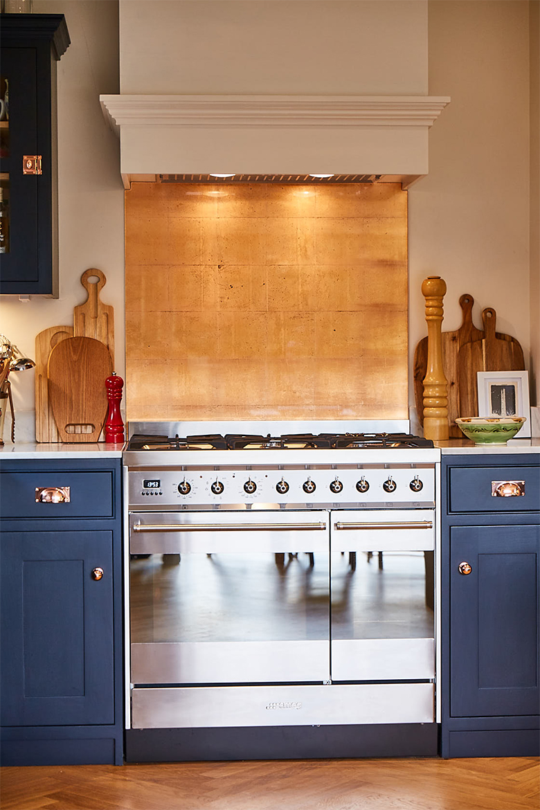 Stainless steel gas range cooker with copper splash back and pained white extraction