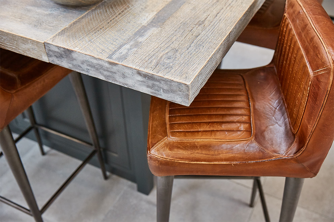 Engineered reclaimed rustic kitchen worktop with brown leather bar stools