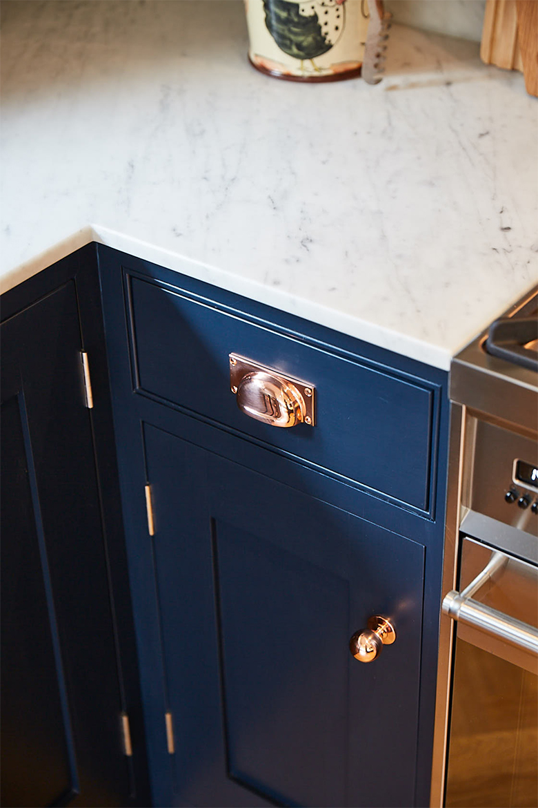 Copper cup handle and copper hinge on dark blue painted bespoke kitchen cabinet