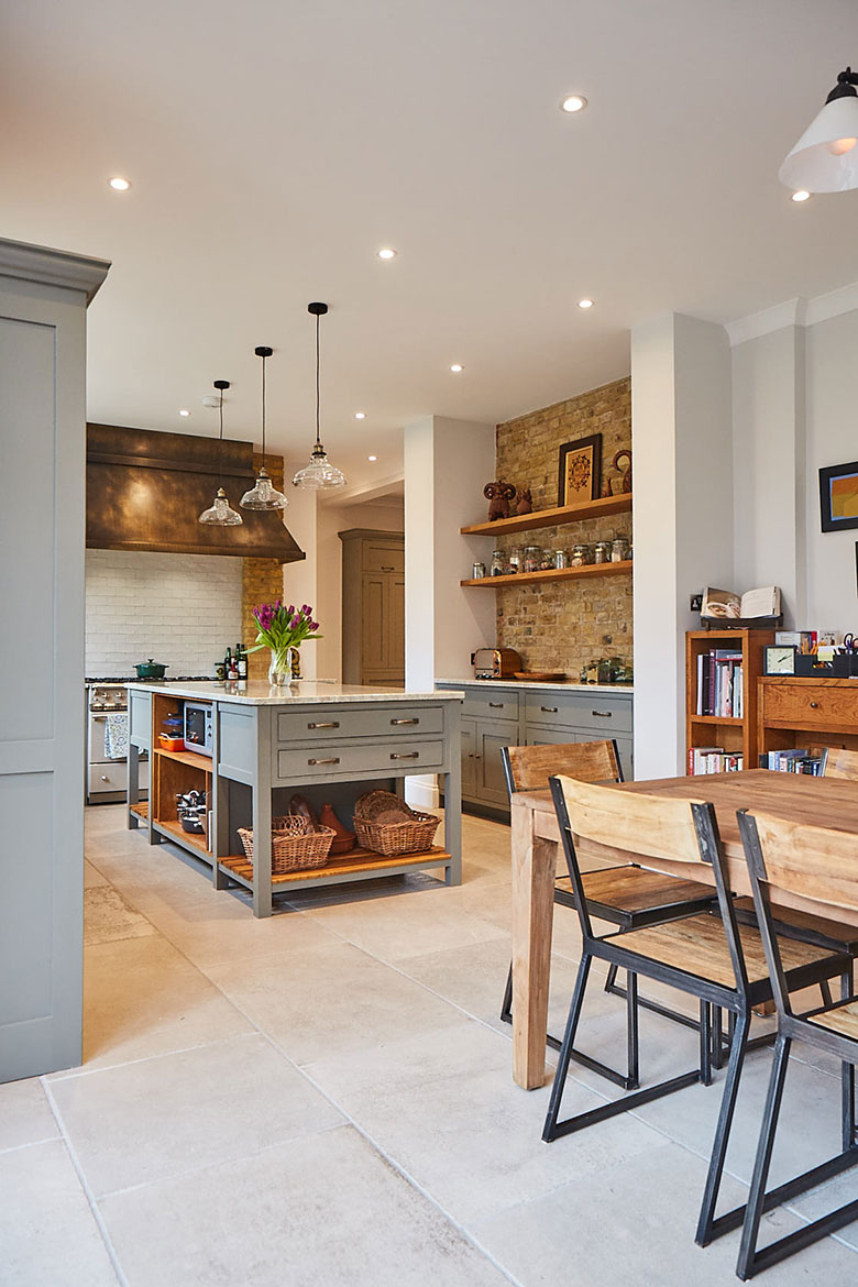 Dining chair in open plan kitchen with yellow London brick and solid oak shelves