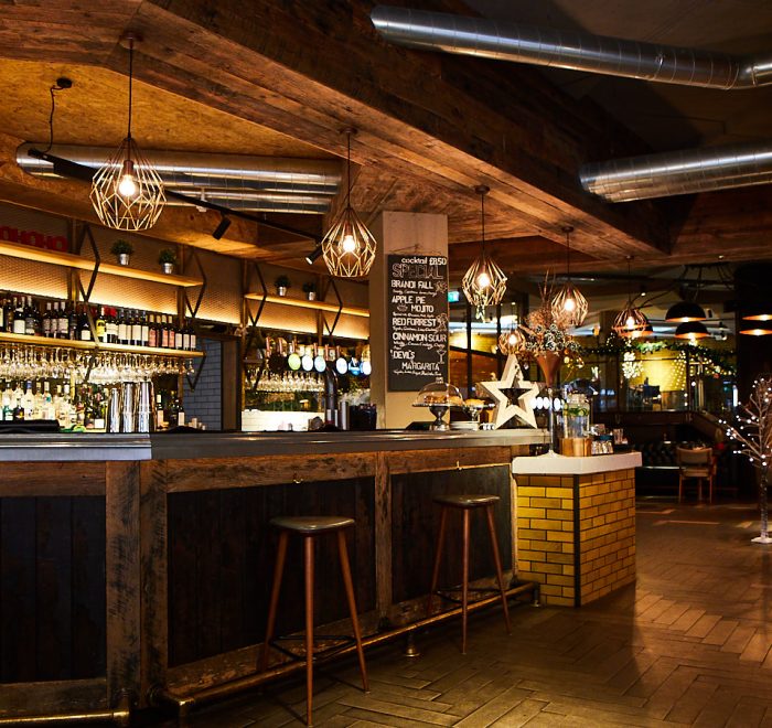 Reclaimed oak bar with stools and wire frame pendant lights above