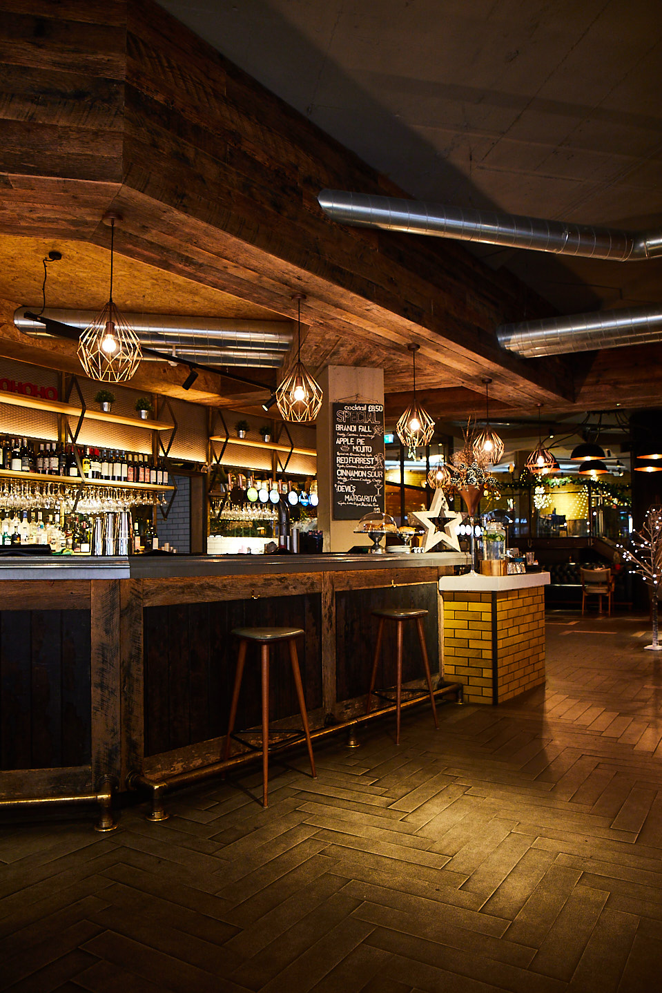 Reclaimed oak bar with stools and wire frame pendant lights above