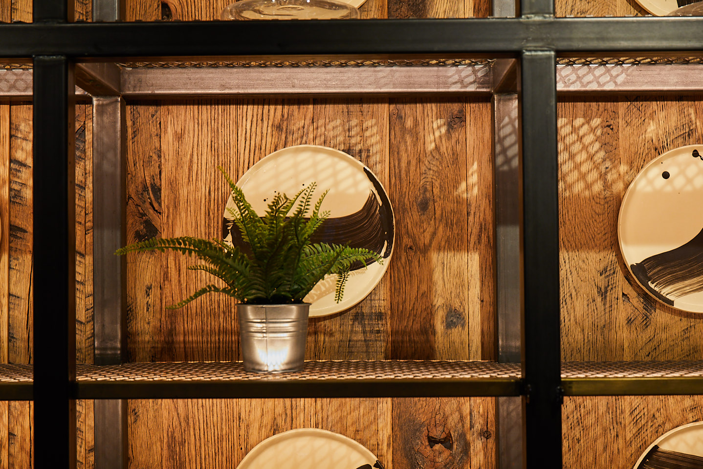 Plant sat on industrial metal shelves with reclaimed timber wall and mirror hung behind