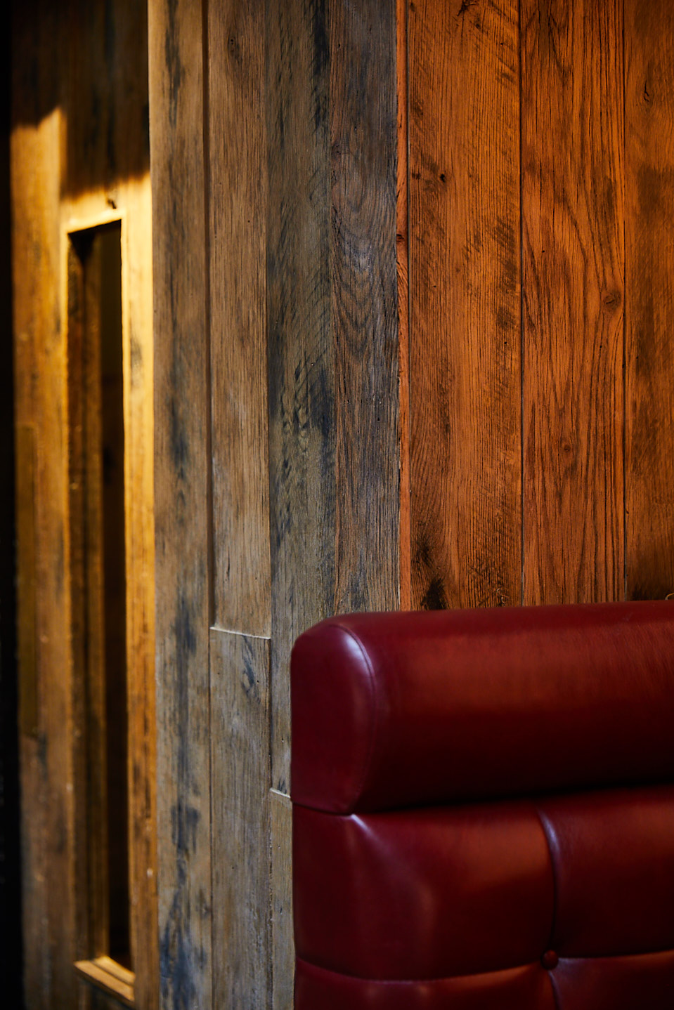 Red leather backrest contrasts against rustic timber wood wall