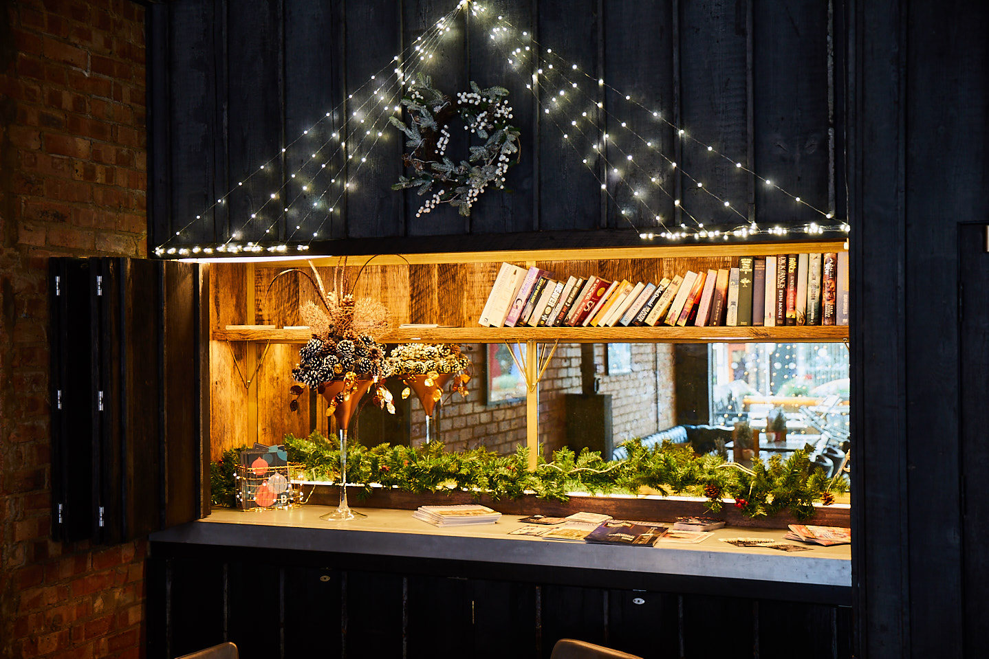 Dark blue pained cladding surrounds feature cabinet with cocktail glass and books