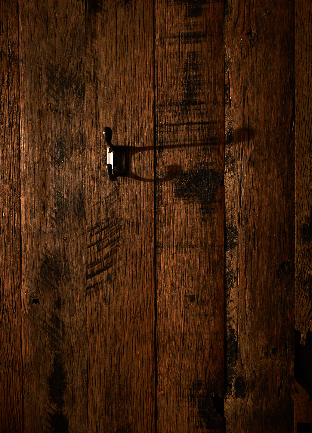 Cast coat hook against reclaimed oak cladded wall