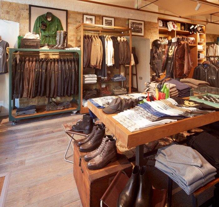 Clothes shop interior with rustic wood floor exposed brick displaying shoes and leather jackets