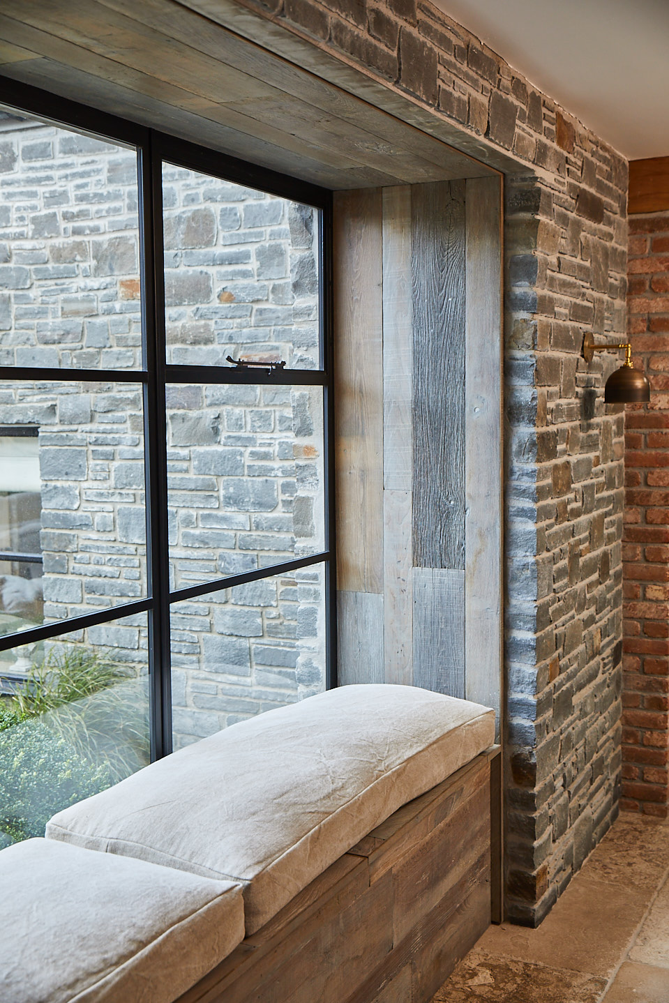 Upholstered window seat with reclaimed timber clad walls and crittall frame