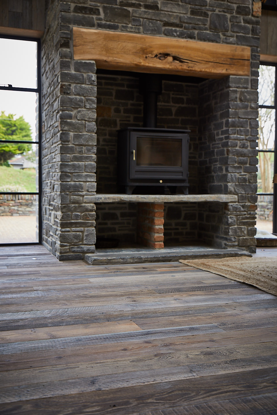 Reclaimed pine floor boards and large stone fireplace