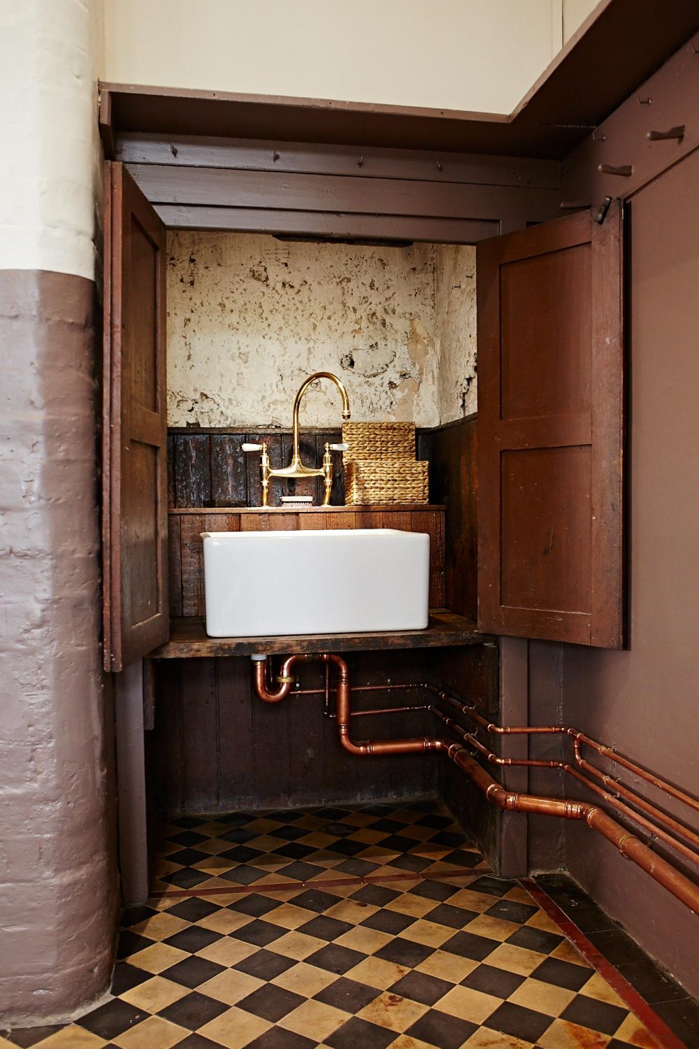 Shaws ceramic sink in original cupboard with exposed copper pipes and brass mixer tap