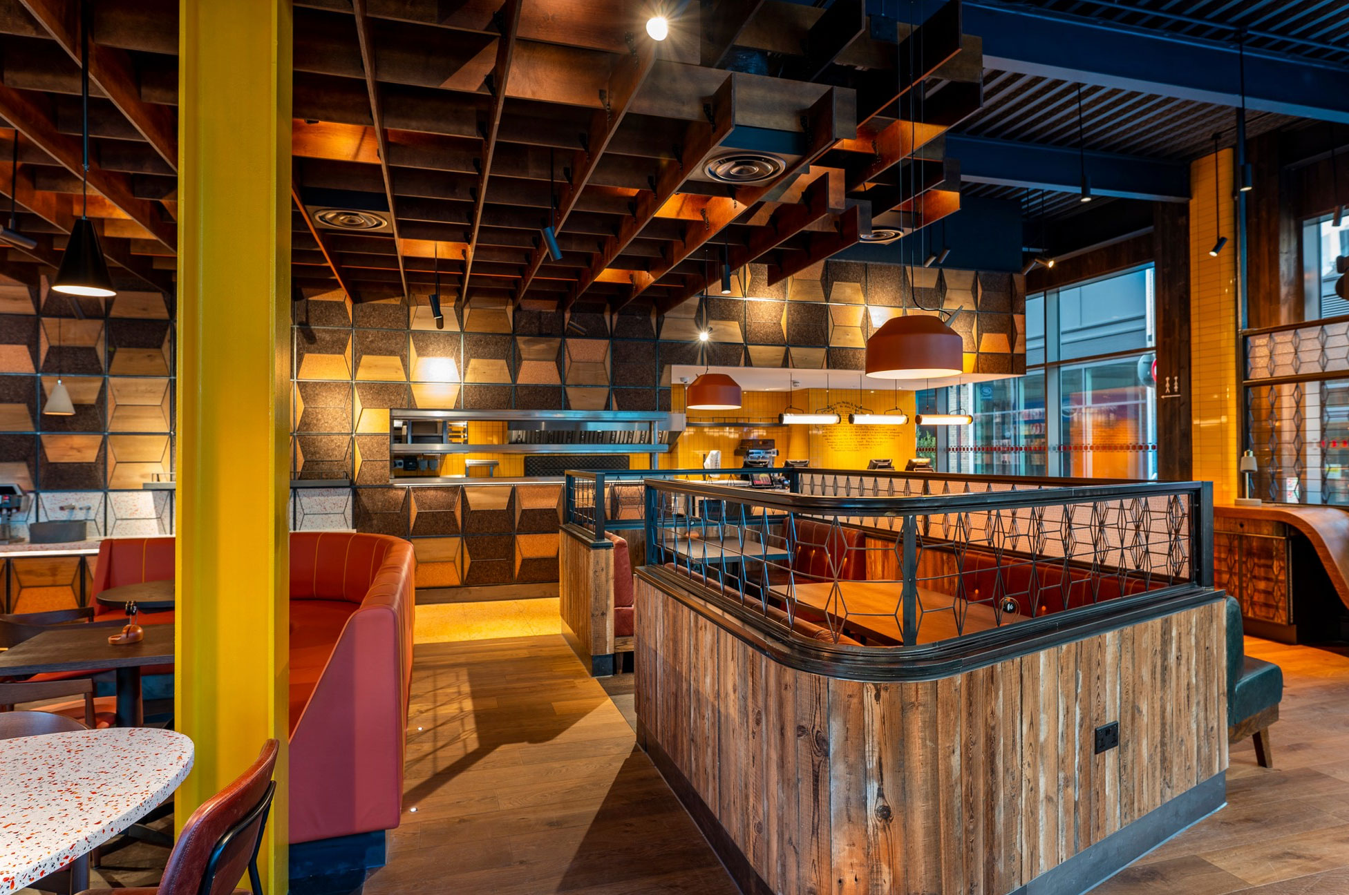 Rustic wood curved around seating area in Nando's with bright yellow RSJ