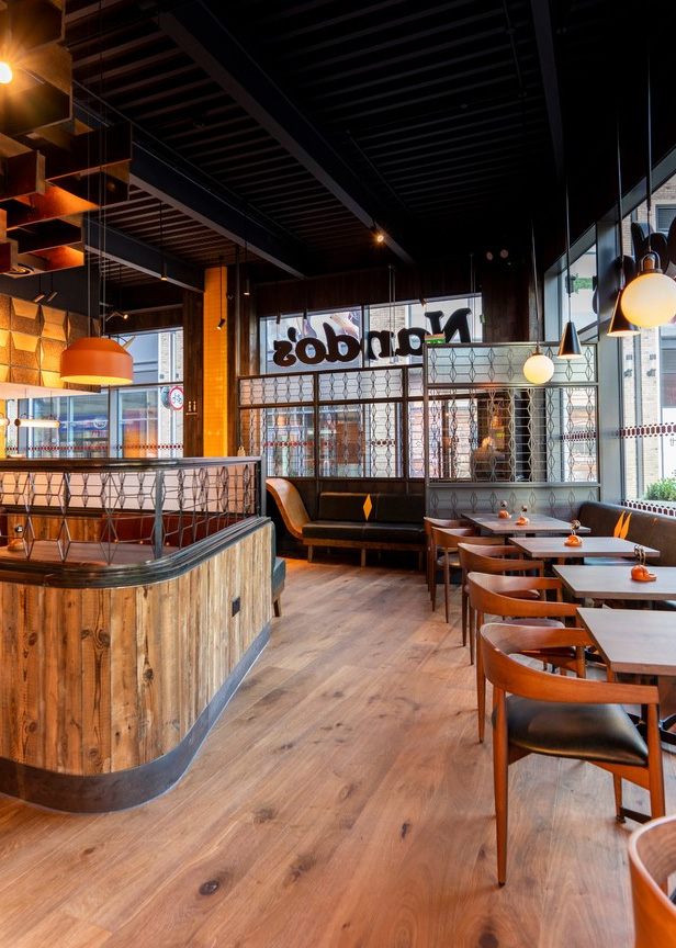 Cladded eating booth sits next to freestanding table and chairs