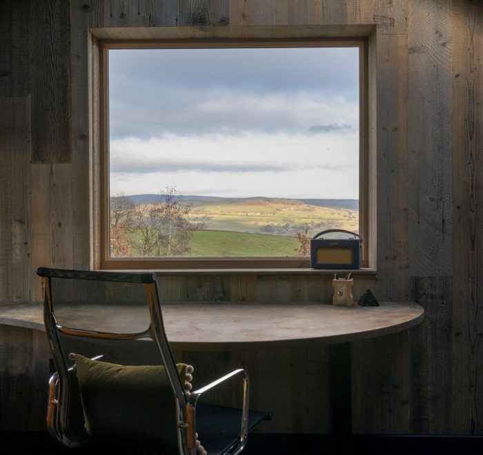 Office desk and chair in front of window in a fully cladded wood room