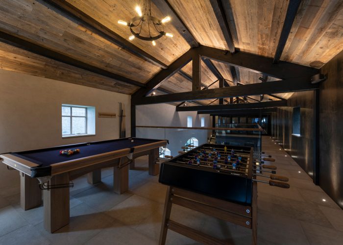 Pool table and foosball table in large room with tiled floor on wood clad ceiling