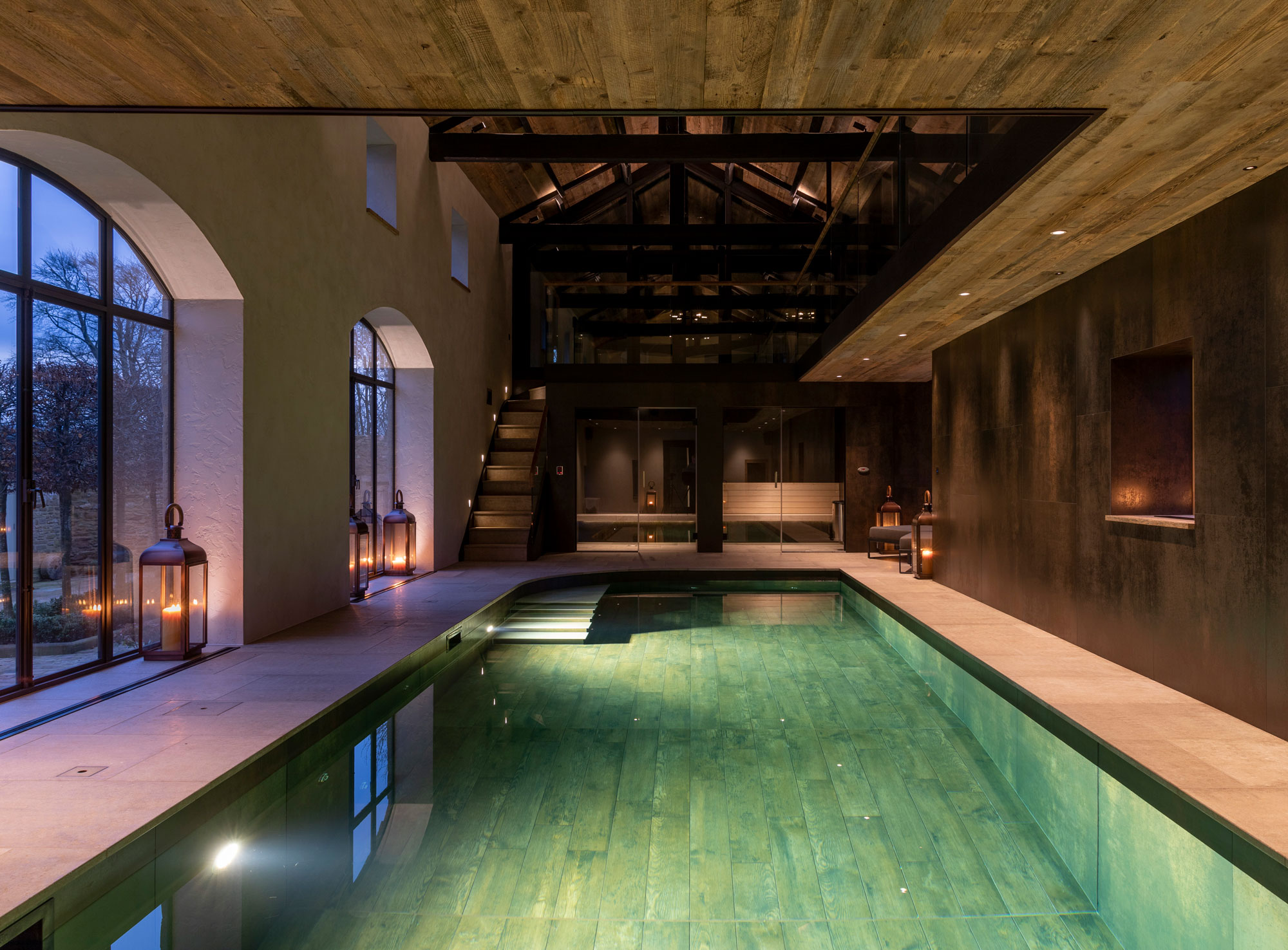 Indoor swimming pool at night with mood lighting and large cream tiles